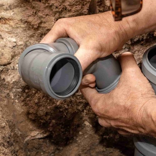 A plumber installs sewer pipes in a bathroom to drain water